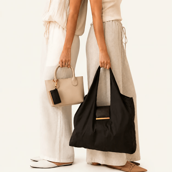 MiniPouch Black, held alongside another bag, lifestyle shot